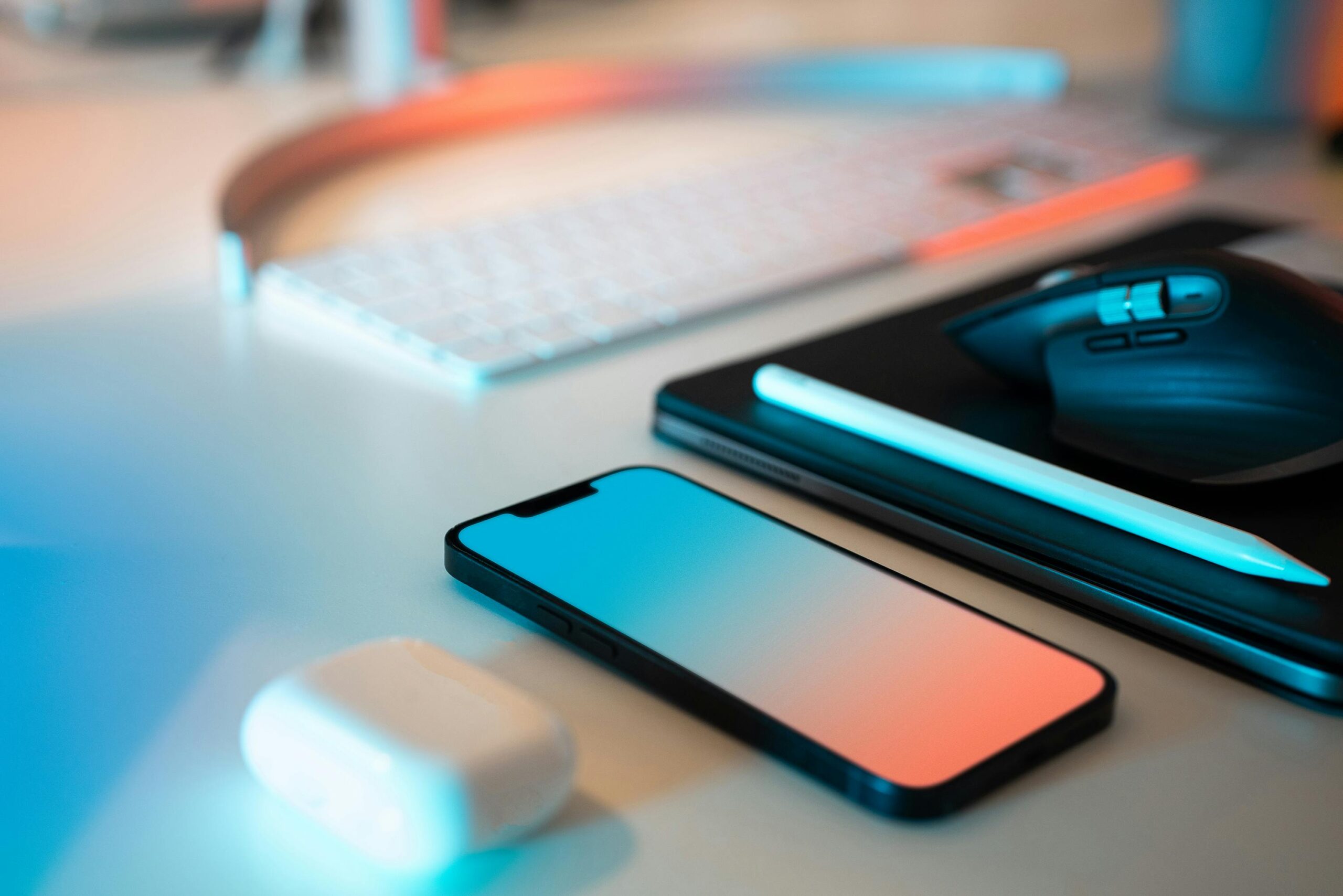 A sleek home office desk setup featuring a smartphone, keyboard, and digital devices under soft lighting.